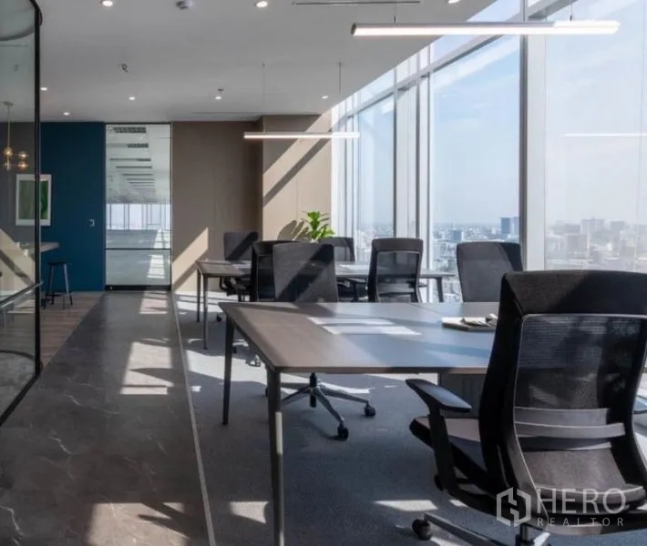 Office Space for rent - Bright workspace with desks and ergonomic chairs beside full-height windows and city views.