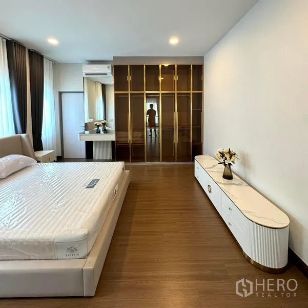 Detached House for rent or sale in Bang Phli, Samut Prakan - Primary bedroom view toward glass wardrobes and a long console cabinet.