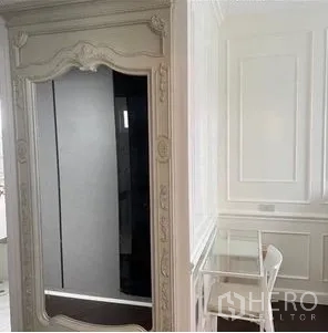 Condominium for rent or sale - Built-in wardrobe with ornate mirror beside a glass writing desk and classic wall paneling.