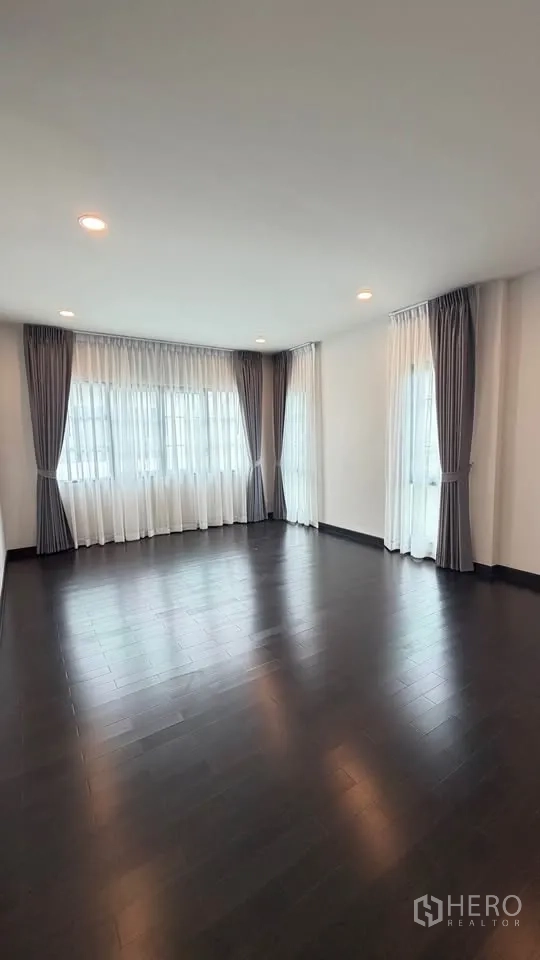 Detached House for rent in Bang Phli, Samut Prakan - Bright corner room with floor-to-ceiling windows and grey drapes.