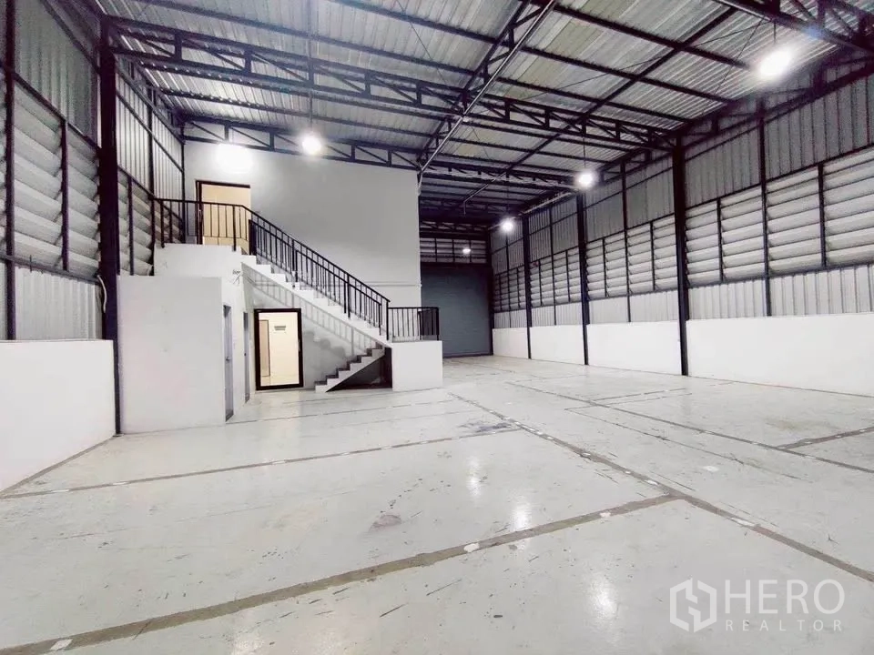 Warehouse for rent in Lam Luk Ka, Pathum Thani - Warehouse floor with side ventilation panels and access to office staircase.