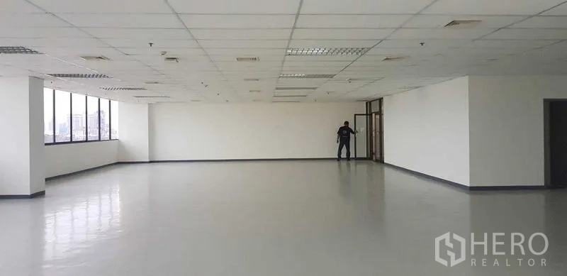 Office Space for rent in Khlong Toei, Bangkok - Spacious open-plan office floor with a long row of corner windows, city views, white walls, grid ceiling lights and ducted air-conditioning.