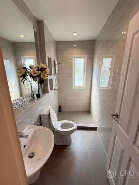 独立式住宅 出售在Bang Khen, Bangkok - 现代卫生间，白色台盆与坐便器，超大镜面与带窗淋浴区。