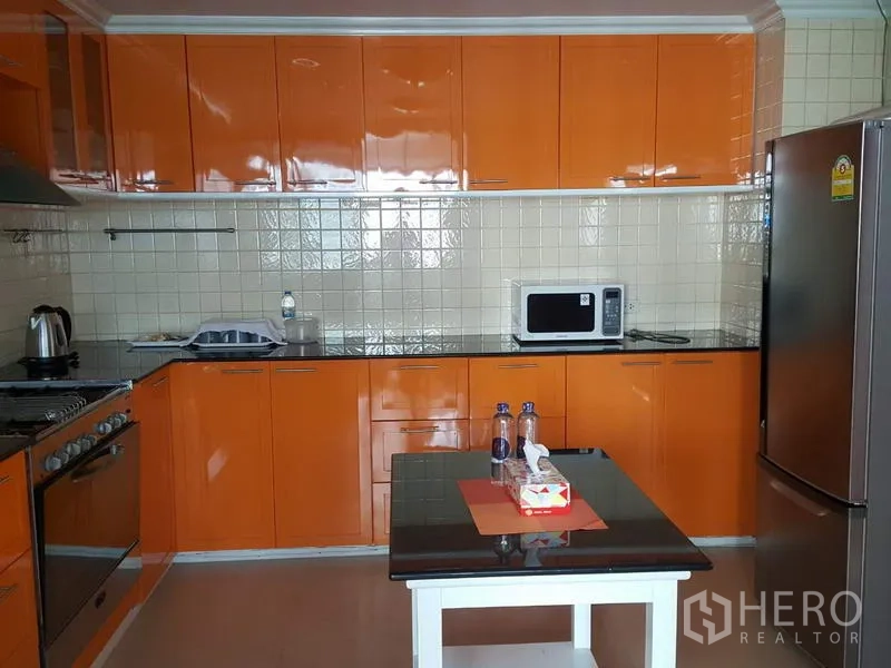 คอนโด ให้เช่าในWatthana, Bangkok - ห้องครัวสมัยใหม่ ตู้สีส้มเงา ผนังกระเบื้อง ไอส์แลนด์เล็ก และเครื่องใช้สแตนเลส