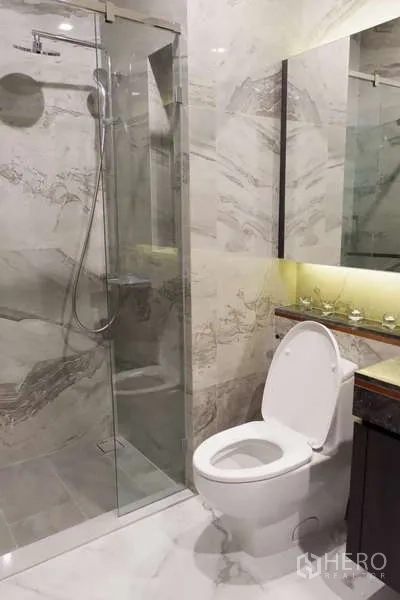 คอนโด ให้เช่า - ห้องน้ำสมัยใหม่พร้อมตู้กระจกกั้นอาบน้ำและผนังลายหินอ่อน