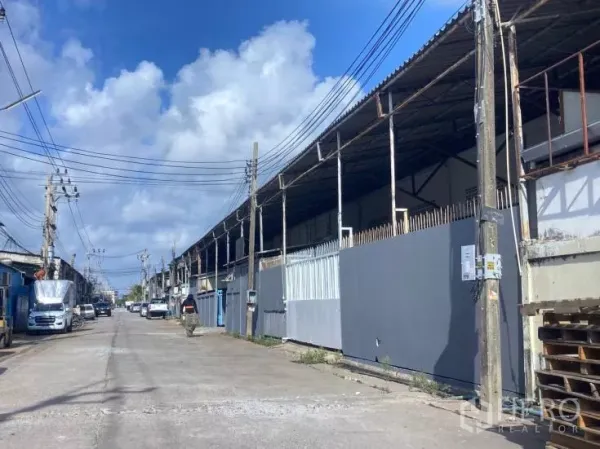 工厂 出租在Bang Phli, Samut Prakan - 工业街道上一排仓库外观，电线杆与金属大门，蓝天白云。