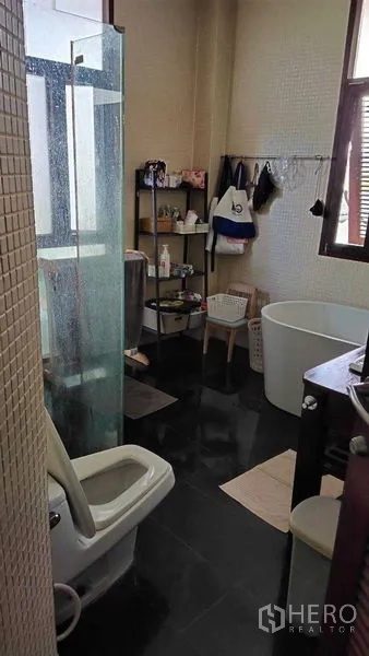 Detached House for sale in Suan Luang, Bangkok - Bathroom with glass shower, freestanding soaking tub, window and storage shelves.