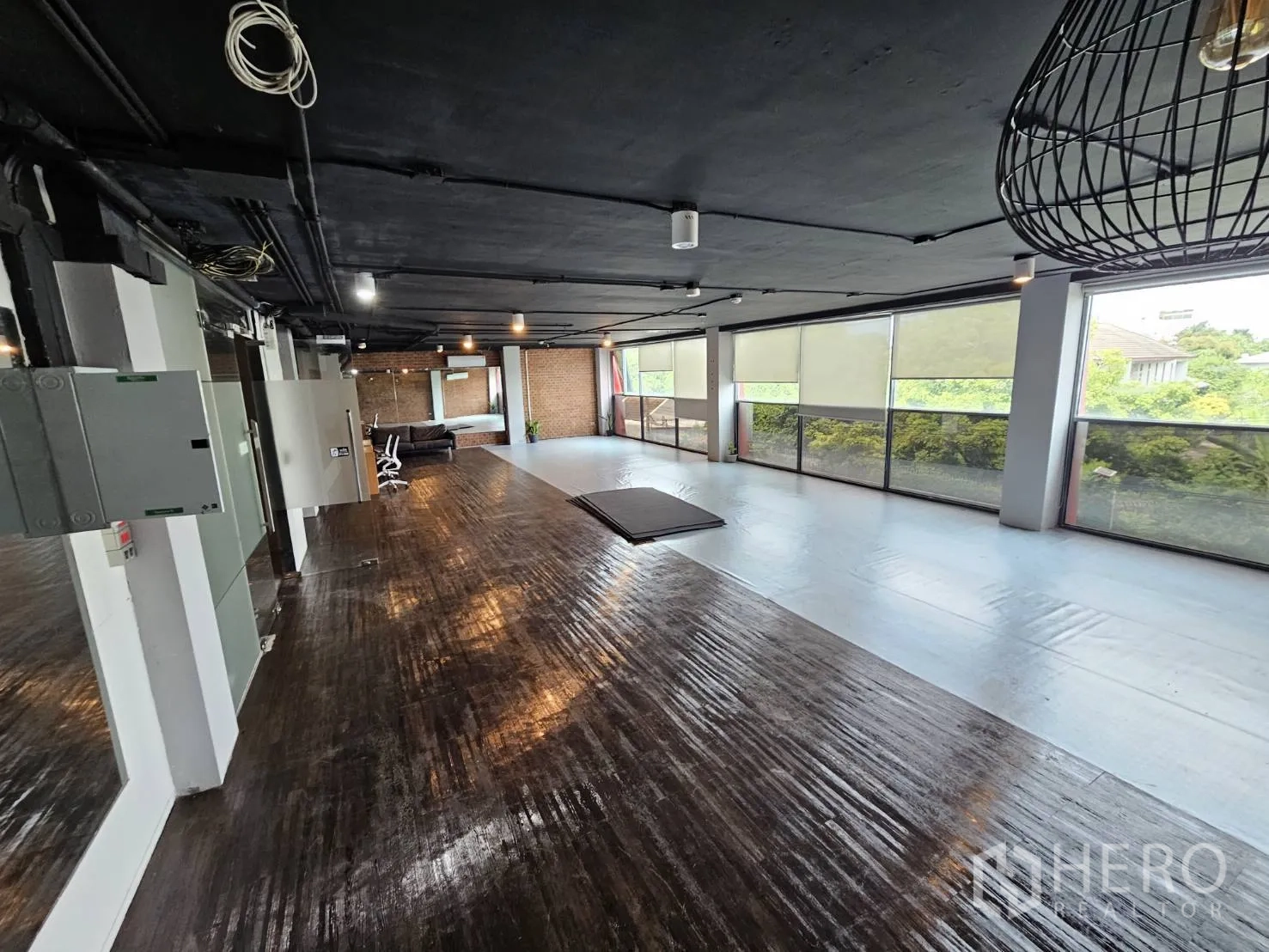 สำนักงาน ให้เช่าในWatthana, Bangkok - พื้นที่ทำงานกว้าง มีแนวหน้าต่างมองเห็นต้นไม้ พื้นไม้เข้มและฝ้าเพดานสีดำสไตล์อินดัสเทรียล.