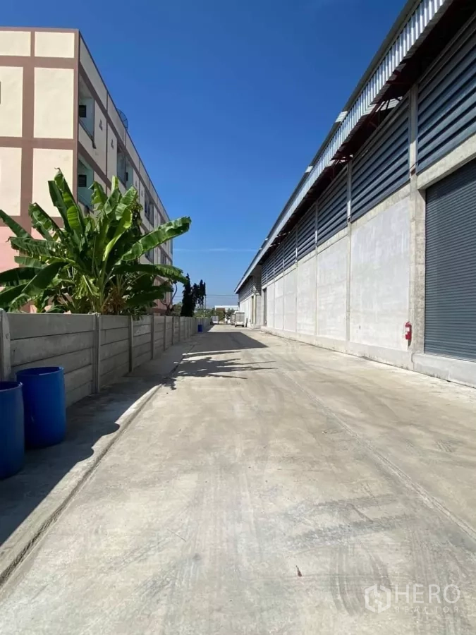 Warehouse for rent in Min Buri, Bangkok - Exterior service lane beside the warehouse with roller shutters and wide access for trailer trucks.