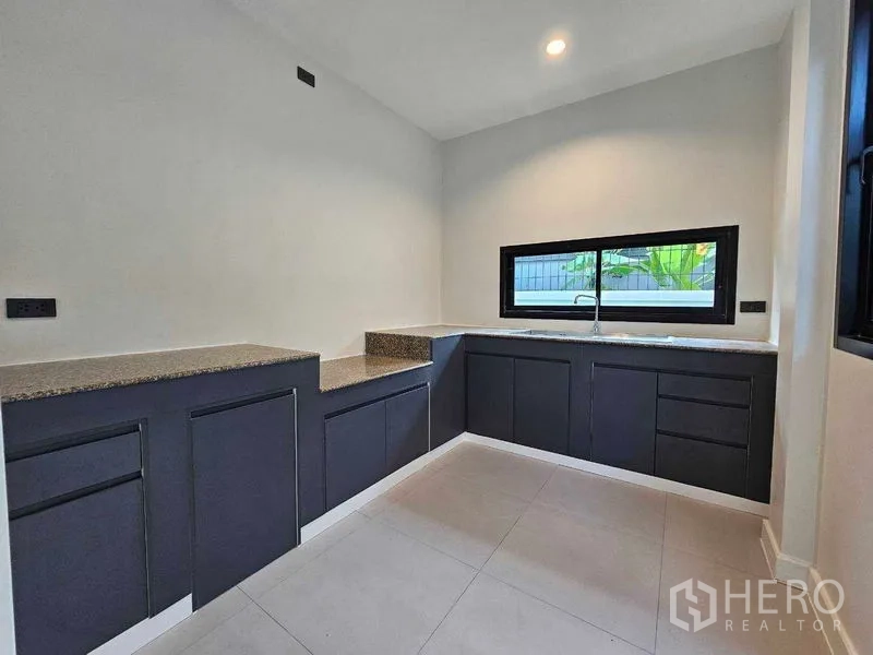 Detached House for sale in Thanyaburi, Pathum Thani - Modern L-shaped kitchen with dark cabinetry and a window above the sink.