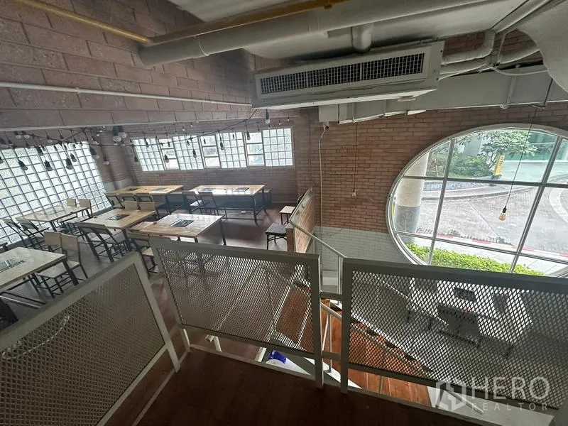 零售空间 出租在Watthana, Bangkok - 砖墙与圆形窗旁的用餐区，临近楼梯。