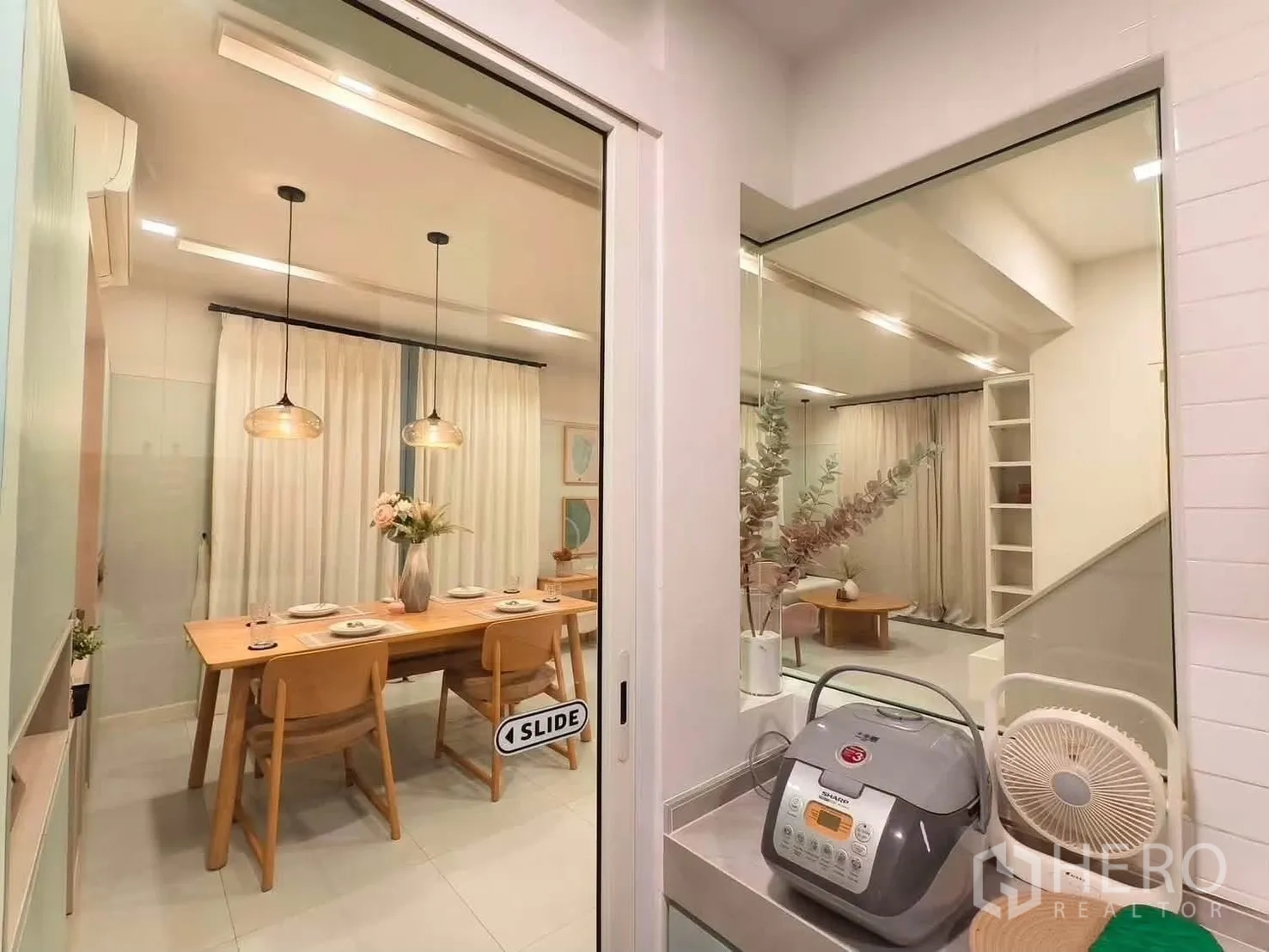 独栋房屋 for rent in Bang Phli, Samut Prakan - 从厨房透过玻璃可见餐桌与带窗帘的客厅。