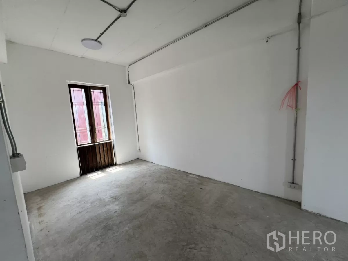 零售空间 出租在Khlong Toei, Bangkok - 简洁白色房间，水泥地面与木框小窗。