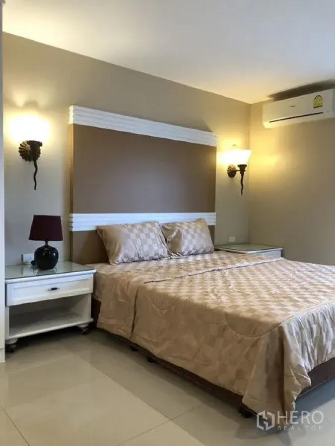 Condominium for rent in Khlong Toei, Bangkok - Cozy bedroom with double bed, bedside tables and wall sconces.