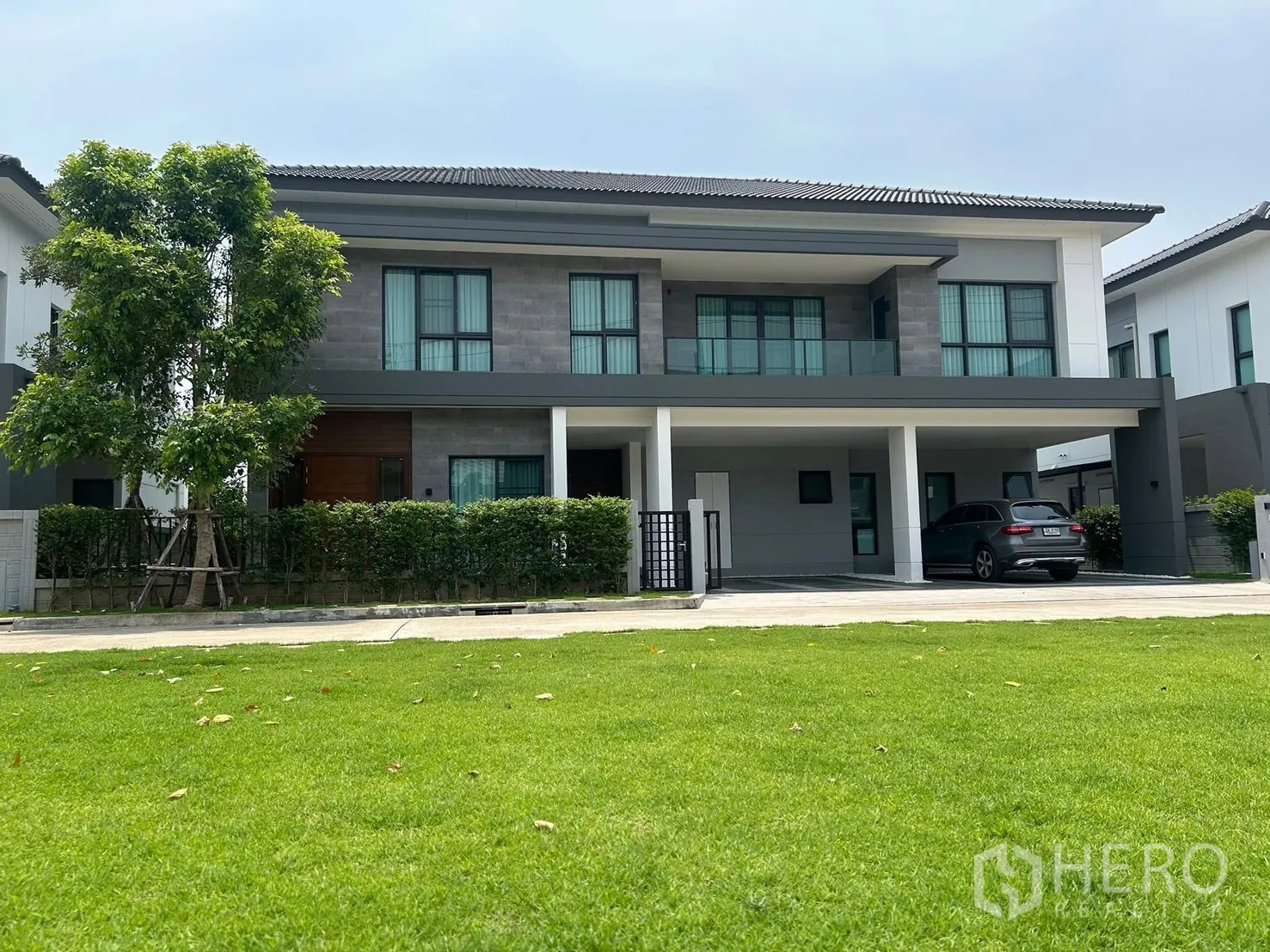 独栋房屋 for rent in Bang Phli, Samut Prakan - 当代双层外立面，设阳台、双车位遮蔽车棚与草坪。