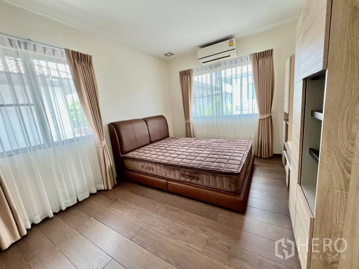 Detached House for rent or sale in Bang Phli, Samut Prakan - Cozy bedroom with brown leather bed, wood flooring and double windows.