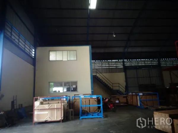 Warehouse for rent or sale in Lat Lum Kaeo, Pathum Thani - Warehouse interior with two-storey office box, staircase, and crates under a high steel roof.