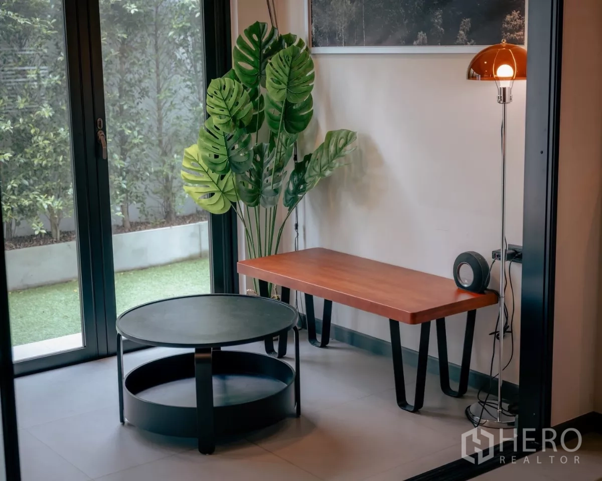 独立式住宅 出租或出售在Bang Phli, Samut Prakan - 角落会客区，茶几、落地灯与绿植，邻近花园门。