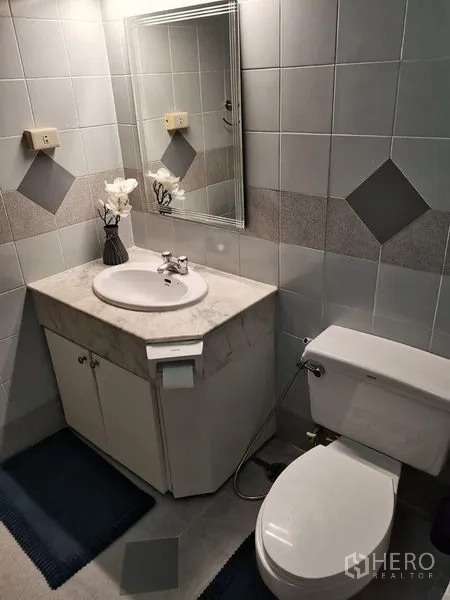 公寓 出租在Khlong Toei, Bangkok - 浴室洗手台，石面台盆、镜子与坐便器。