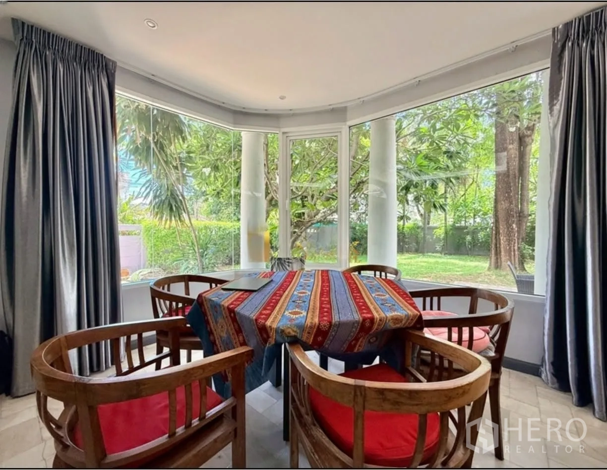 บ้านเดี่ยว for rent in Phra Khanong, Bangkok - มุมรับประทานอาหารพร้อมเก้าอี้ไม้และหน้าต่างบานใหญ่เห็นวิวสวน