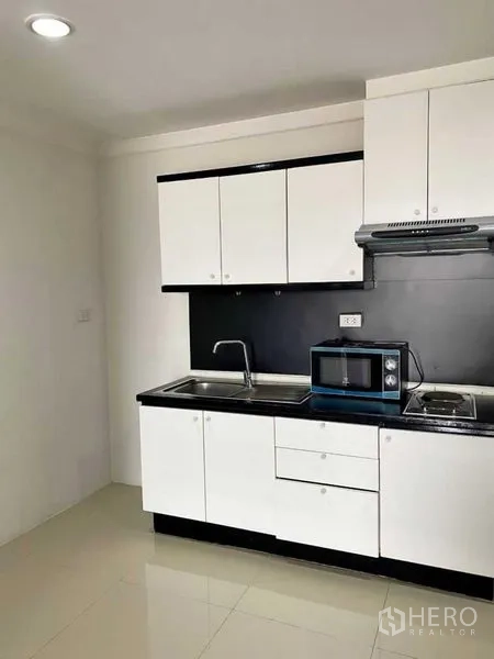 公寓 出租在Khlong Toei, Bangkok - 小厨房配双水槽、抽油烟机、灶台与微波炉。