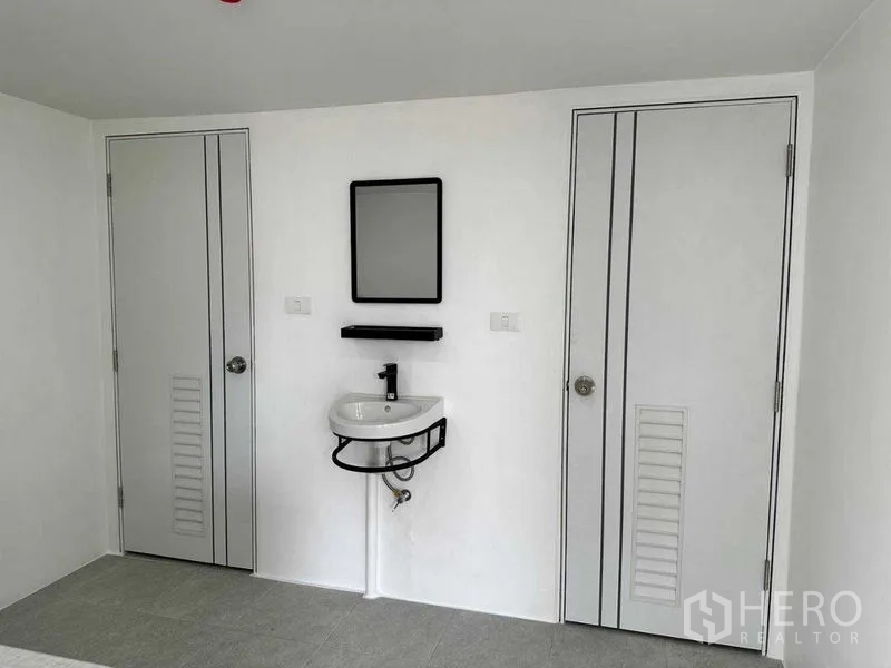 Office Space for rent or sale in Khlong Toei, Bangkok - Restroom area with two doors, a wall-mounted sink and mirror.