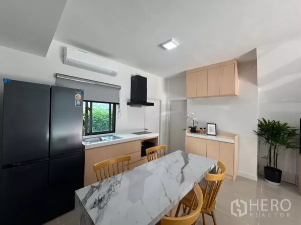 Townhouse for rent in Bang Phli, Samut Prakan - Kitchen with marble dining island, wood cabinetry, and matte black refrigerator