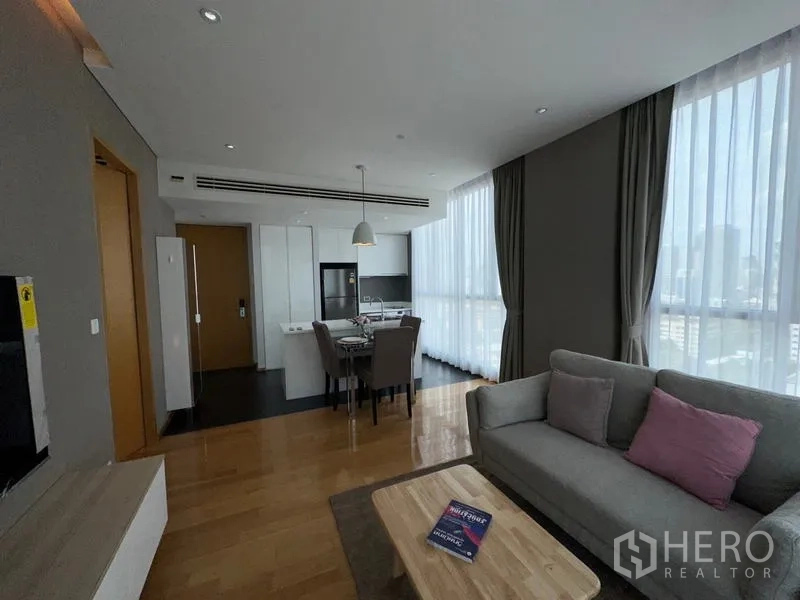 公寓 出租在Watthana, Bangkok - 客厅配沙发与城市景观，旁连餐桌和白色一体化厨房。