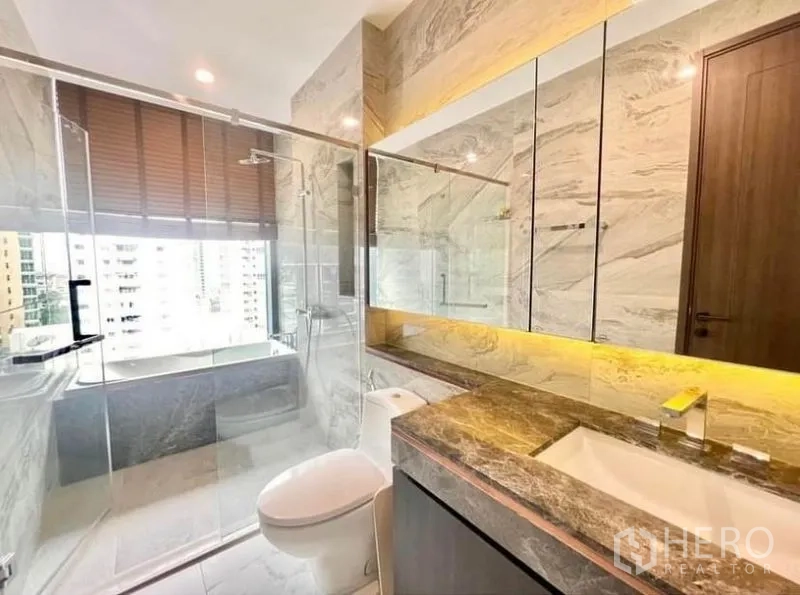 Condominium for rent in Watthana, Bangkok - Marble bathroom with glass shower, illuminated mirror and city-view window.