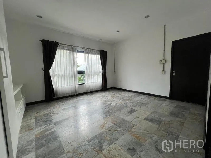 Townhouse for rent in Phaya Thai, Bangkok - Spacious room with large windows, dark curtains and stone-pattern floor tiles.