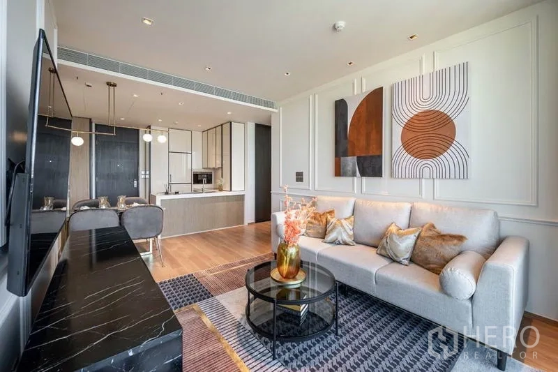 คอนโด ให้เช่าในKhlong Toei, Bangkok - ห้องนั่งเล่นสว่าง โซฟา งานศิลป์ผนัง และครัวแบบเปิดของคอนโดสมัยใหม่