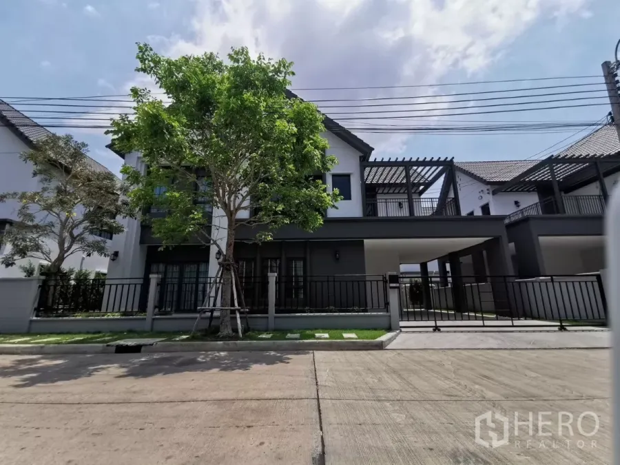 Detached House for rent in Bang Phli, Samut Prakan - Modern two-storey detached house with front gate, carport and tree-lined frontage in a gated community of Bang Phli.