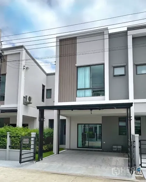 Townhouse for rent in Bang Phli, Samut Prakan - Modern two-storey townhouse exterior with a covered two-car carport and sliding glass doors.