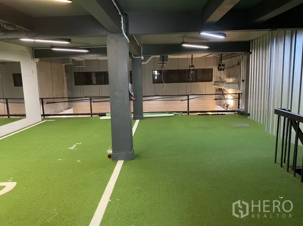 พื้นที่ขายปลีก ให้เช่าในPhaya Thai, Bangkok - ชั้นลอยปูหญ้าเทียม พร้อมไฟเส้น LED และราวกันตก มองลงสู่พื้นที่ค้าปลีกด้านล่าง.