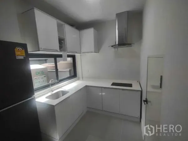 独立式住宅 出租在Khan Na Yao, Bangkok - 白色L型厨房，带水槽、窗户、灶台与不锈钢烟机。