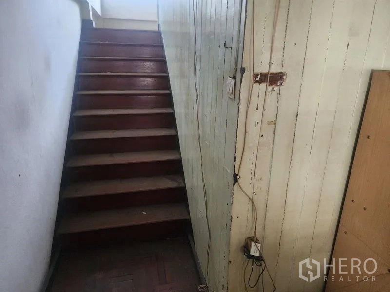 Detached House for rent in Watthana, Bangkok - Narrow wooden staircase leading to the upper floor with aged paintwork.