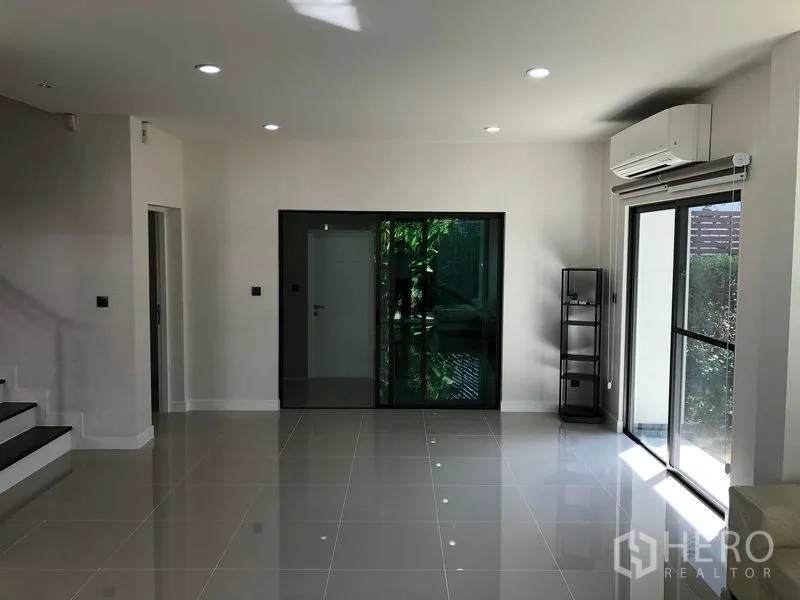 Detached House for rent in Bang Kapi, Bangkok - Open-plan ground floor with glossy tiles, stairs and dual sliding doors to the yard.