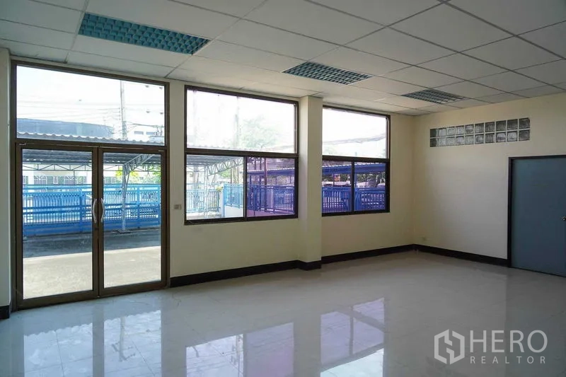 Factory for rent in Bang Sao Thong, Samut Prakan - Ground‑floor office or reception with glass door and full‑height windows.