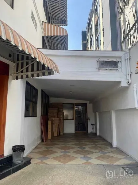 店屋 出租在Phaya Thai, Bangkok - 商铺入口及有顶停车区，棋盘格地砖与条纹遮阳篷。