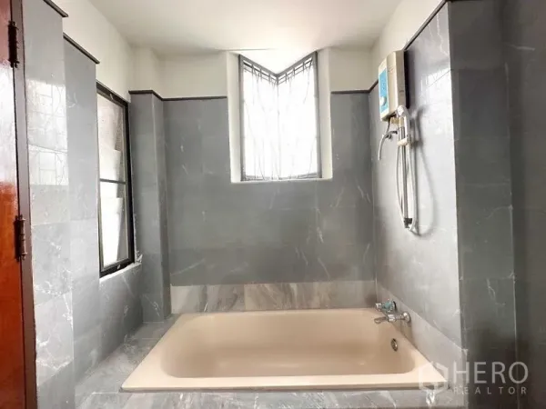 带办公室的家 出租在Phra Khanong, Bangkok - 灰色瓷砖浴室，内置浴缸、窗户护栏与热水器。