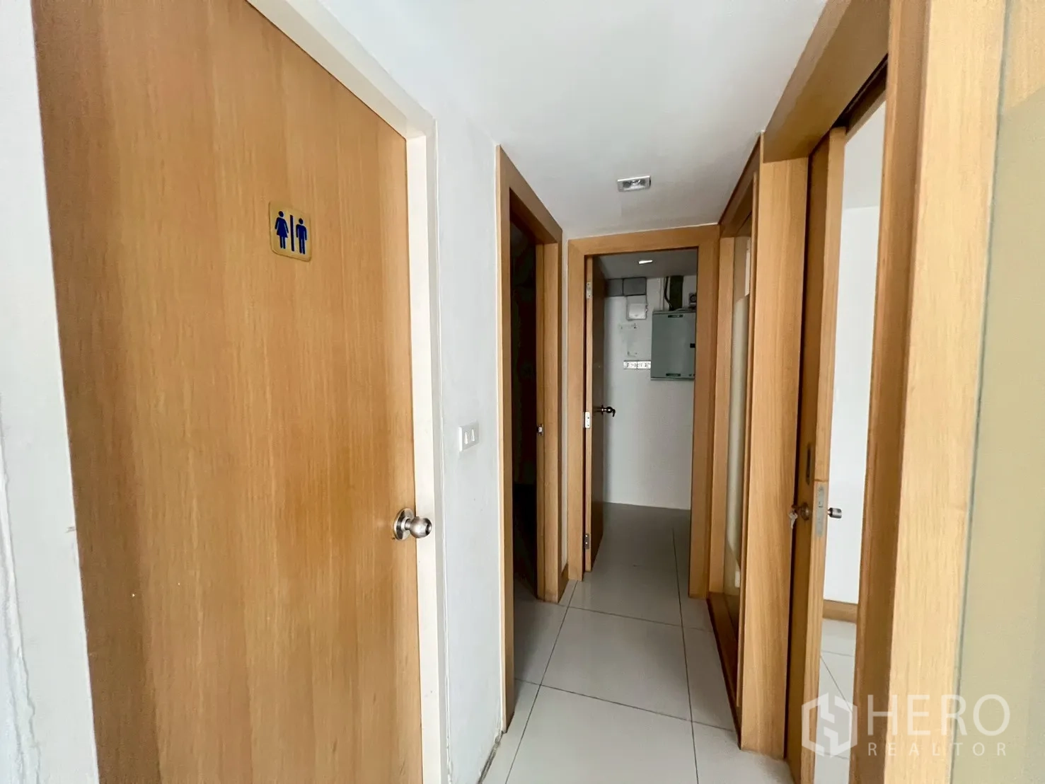พื้นที่ขายของ for rent in Watthana, Bangkok - ทางเดินที่มีประตูไม้หลายบาน รวมถึงประตูห้องน้ำที่มีป้ายสัญลักษณ์