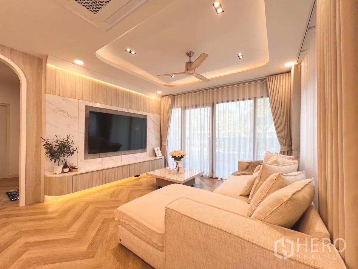 Detached House for rent in Bang Phli, Samut Prakan - Cozy living room with marble TV wall, recessed lighting and sectional sofa.