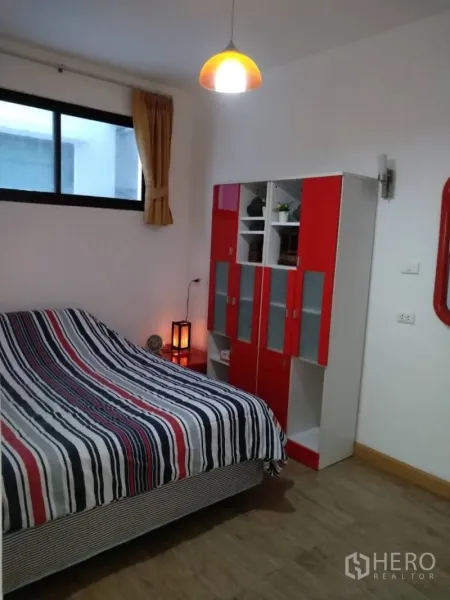 Condominium for rent in Watthana, Bangkok - Cozy bedroom with striped bedding, red-and-white wardrobe and a window.