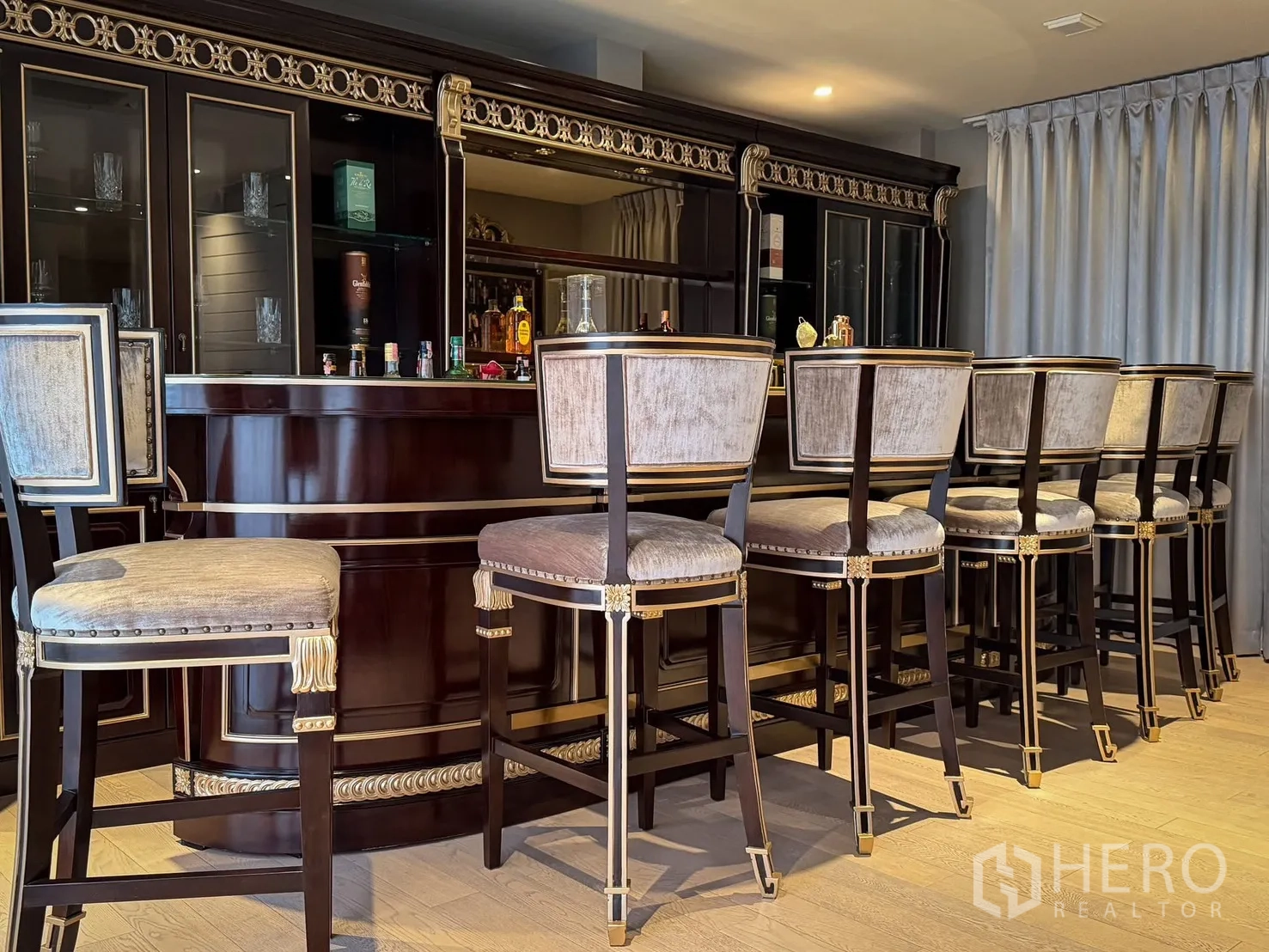 Detached House for rent or sale in Lak Si, Bangkok - Home bar with long counter, glass cabinetry, and upholstered bar stools.