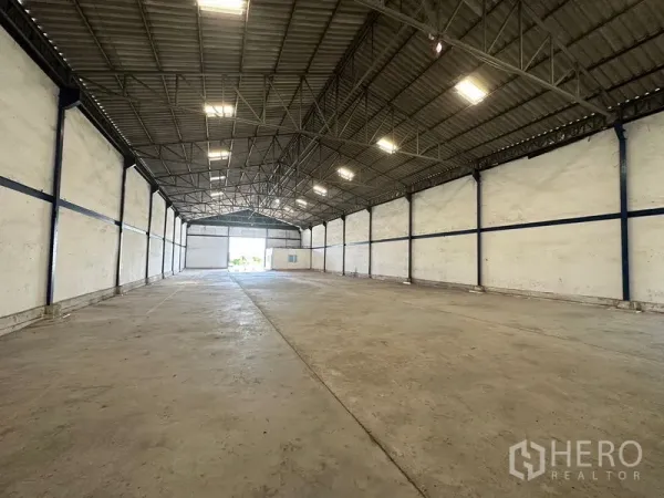 Warehouse for rent in Bang Bo, Samut Prakan - Clear‑span warehouse interior showing high steel truss roof, bright lighting, and concrete floor.