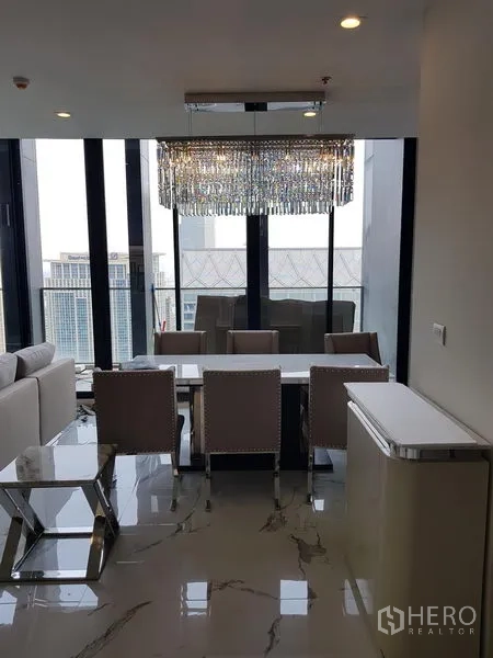 คอนโด ให้เช่าในPathum Wan, Bangkok - มุมรับประทานอาหารใต้โคมไฟคริสตัล มองออกไปยังหน้าต่างสูงและทิวทัศน์เมือง