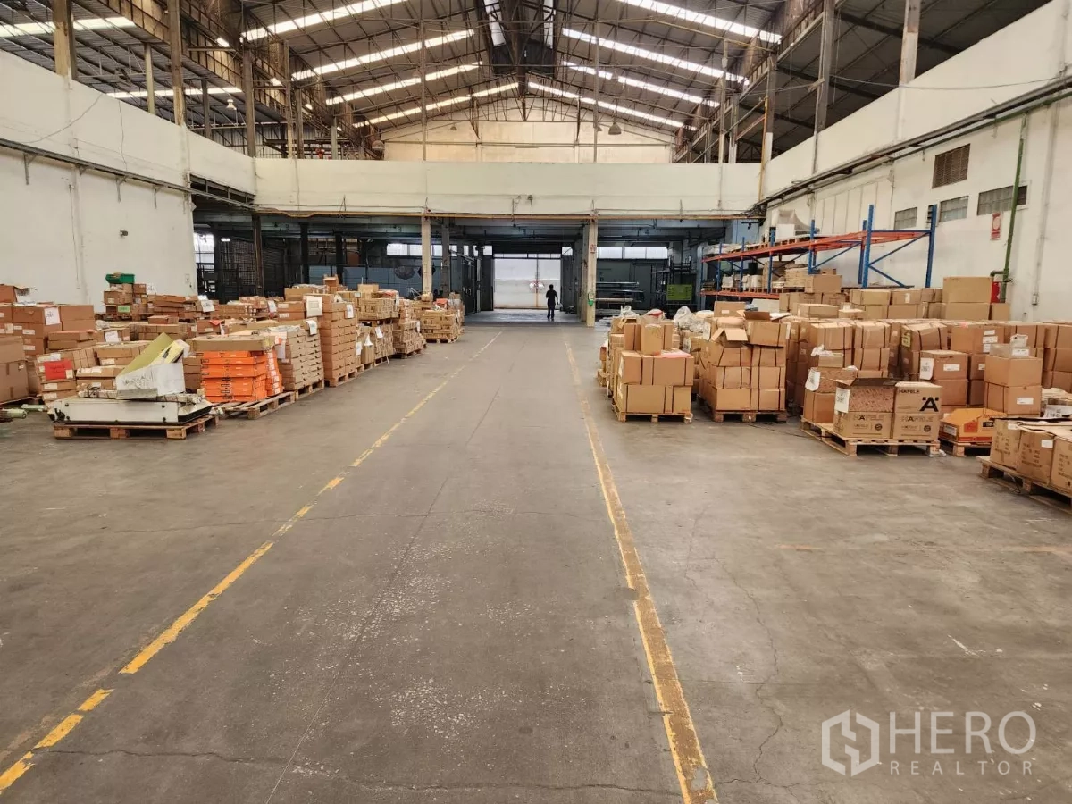 工厂 出租在Mueang Samut Sakhon, Samut Sakhon - 仓库通道，整齐托盘纸箱与高挑屋顶。