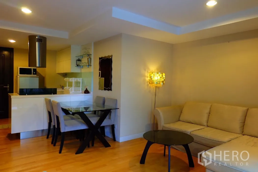 คอนโด ให้เช่าในPhaya Thai, Bangkok - ห้องนั่งเล่นและรับประทานอาหารแบบโอเพ่นพร้อมโซฟาเข้ามุมสีเบจ โต๊ะกระจก และครัวขนาดกะทัดรัดพร้อมเคาน์เตอร์