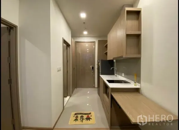 Condominium for sale in Huai Khwang, Bangkok - Entry corridor with long galley kitchen, built-in cabinetry, sink and foldout counter.
