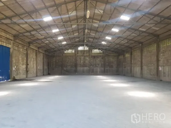 Warehouse for rent in Pak Kret, Nonthaburi - Spacious warehouse interior with high steel-truss roof, skylights and smooth concrete floor.